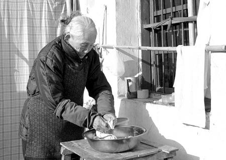 图为裘兴月老人正在帮半瘫夫妇洗衣服.(记者 冯小平 摄)