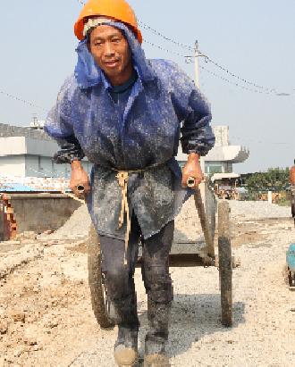 下午3时30分,大成路一建筑工地,工人正在运送搅拌好的水泥.