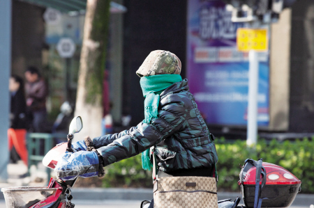 昨天,风有点大,户外较冷.一名市民裹得严严实实,骑行在百丈东路上.